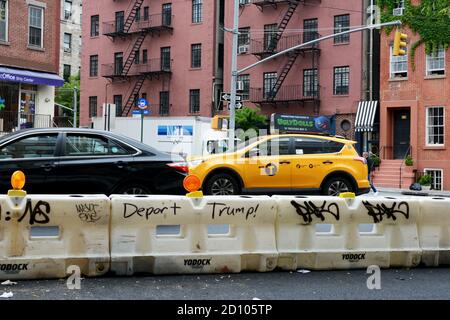 NEW YORK, USA - 10. MAI 2019: Graffiti mit dem Slogan - Deport Trump! - an einer Verkehrsbarriere auf der 7th Avenue, New York City am 10. Mai 2019. Verkehr Stockfoto