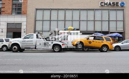 NEW YORK, USA - 10. MAI 2019: Das abgebrochene gelbe Taxi, das von einem Bergungsfahrzeug vor einer Chase-Bankfiliale in New York City abgeschleppt wurde, wurde am Mai abgerissen Stockfoto