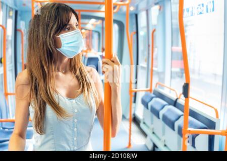 Frau mit Gesichtsmaske, die während des Covid-19-Ausbruchs mit der Straßenbahn unterwegs war. Hochwertige Fotos Stockfoto
