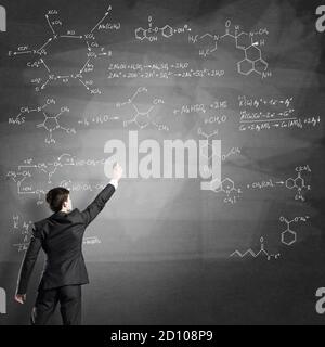 Wissenschaftler schreibt Formeln auf Tafel Stockfoto