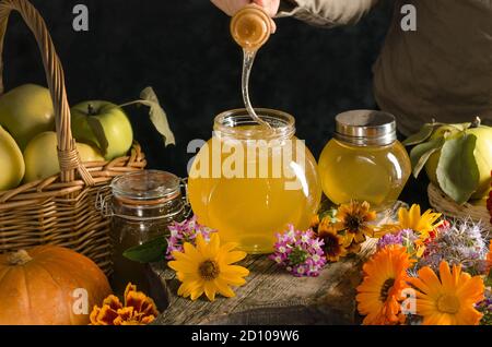 Honig in einem Glas mit einem Honigstock in einem dunklen Stil. Stockfoto