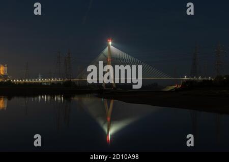 Die Flintshire Bridge, die nachts beleuchtet ist und den Fluss Dee vom Connah's Quay aus überspannt, ist mit Kabelgestellen ausgestattet. Fächerartige Struktur, die sich in der gespiegelten Mündung widerspiegelt Stockfoto