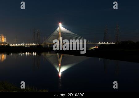 Die Flintshire Bridge, die nachts beleuchtet ist und den Fluss Dee vom Connah's Quay aus überspannt, ist mit Kabelgestellen ausgestattet. Fächerartige Struktur, die sich in der gespiegelten Mündung widerspiegelt Stockfoto