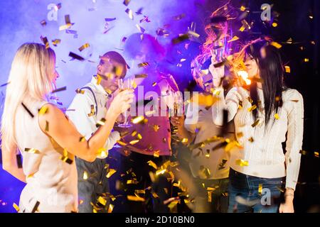 Gemeinsam Spaß haben. Gruppe von schönen jungen glücklich Multi-Rennen Menschen tanzen halten Champagner in goldenen Konfetti und lächelnd Nachtleben neue Jahr Promi Stockfoto