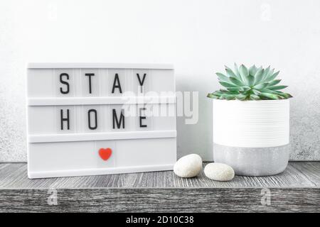 Lightbox mit Text BLEIB ZU HAUSE auf einem Holztisch mit echeveria im Keramiktopf. Sicher bleiben, drinnen bleiben Konzept - Bild Stockfoto