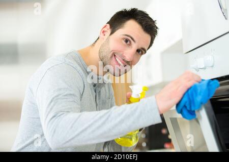 Glücklicher Mann, der den Ofen putzt Stockfoto