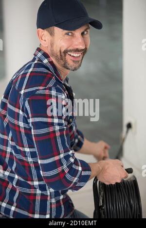 Glücklicher männlicher Baumeister, der Kabel hält Stockfoto