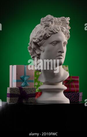 Weiße Gipsstatue von Apollo Belvedere, Geschenkboxen und Verpackungen, in blauem Konturlicht auf mehrfarbigem Hintergrund. Stockfoto