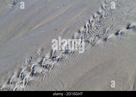 Wasserbach, der über den Strand zum Meer führt Bei Ebbe Stockfoto