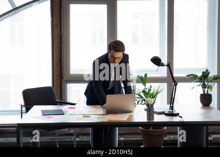 Viel beschäftigter junger Manager, der die Präsentation am Computer überprüft. Stockfoto