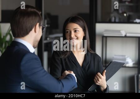 Männlicher Führer schüttelt Hände mit indischer Ethnie weibliche Angestellter. Stockfoto