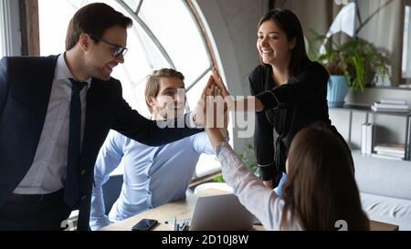 Glückliche motivierte multirassische Mitarbeiter geben hohe fünf. Stockfoto
