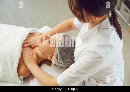 Masseur macht professionelle manuelle entspannende Massage für Frauen Gesicht und Oberer Schultergurt Stockfoto