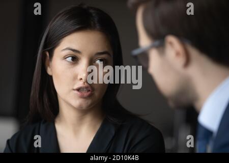 Serious junge indische Ethnizität Geschäftsfrau im Gespräch mit männlichen selbstbewussten Partner. Stockfoto