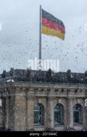 Regentropfen auf dem Fenster mit deutscher Flagge im Hintergrund in Berlin, Deutschland Stockfoto