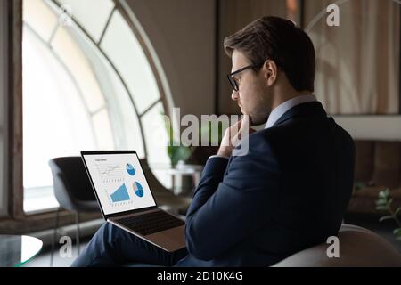 Fokussierte qualifizierte junge 30s männlichen Marketing-Spezialist Analyse Grafiken. Stockfoto