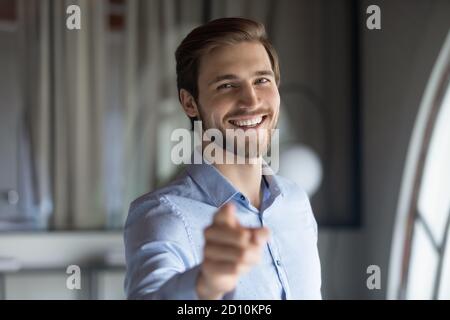 Lächelnd jung hübsch männlich hr Manager zeigt feiner auf Kamera. Stockfoto