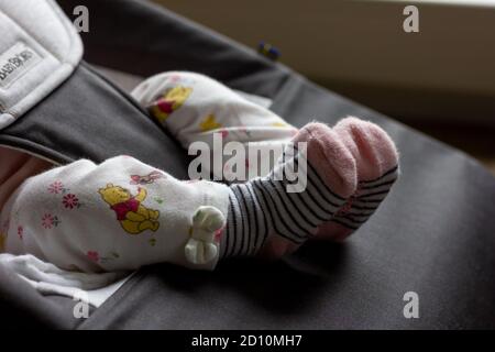 Brecht, Belgien - 9. September 2020: Ein Nahaufnahme Porträt von den Beinen und Füßen eines Babys in einem Relax-Sitz in flauschigen niedlichen Hosen und blau sitzen Stockfoto