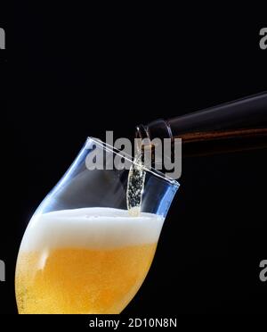 Bierflasche Gießen goldenes Ale Bier in einem Glas, schwarzer Hintergrund, Nahaufnahme abgeschnitten Porträt Ansicht, Kopierraum Stockfoto