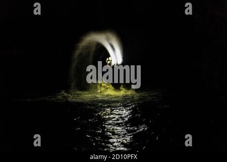 Flyboarding bei Nacht in einem Steinbruch in der Tschechischen Republik. Ein nicht identifizierter Mann führt nachts das Flyboarding durch. Bewegungseffekt, Langzeitbelichtung. Stockfoto