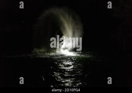 Flyboarding bei Nacht in einem Steinbruch in der Tschechischen Republik. Ein nicht identifizierter Mann führt nachts das Flyboarding durch. Bewegungseffekt, Langzeitbelichtung. Stockfoto