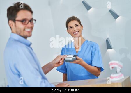 Patient zahlt für Zahnarztbesuch in der Klinik Stockfoto