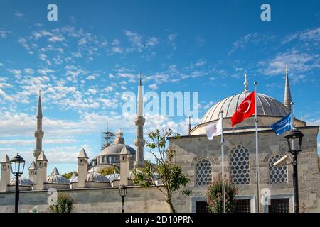 Die Kuppel und die Minarette der Blauen Moschee ragen über kleinere Gebäude mit der Türkischen Flagge in Istanbul. Stockfoto