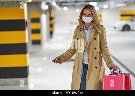 Erwachsene Frau mit Einkaufstaschen in Maske in Tiefgarage Los Stockfoto