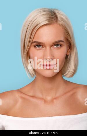 Freistil. Junge blonde Frau oben isoliert auf blau lächelnd zuversichtlich Nahaufnahme Stockfoto