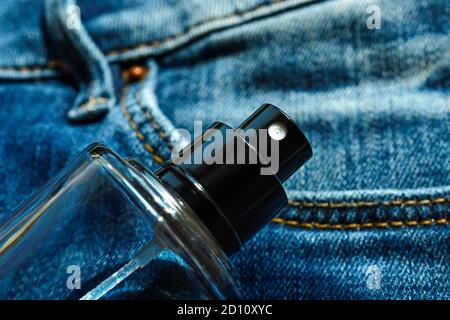 Glasflasche mit unisex duftendem Parfüm oder duftendem WC-Wasser auf einem blauen Denim. Lässiger leichter Duft für alle. Draufsicht. Stockfoto