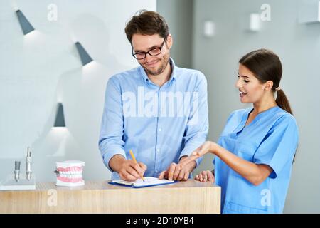 Patienten Unterzeichnung Dokumente in der Zahnklinik Stockfoto