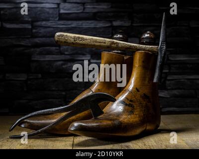 Ein Paar klassischer Schuster aus Holz und traditionelle Schuster Hammer 7 Zange dramatisch auf Holzbretter mit Schiefer beleuchtet Hintergrund Stockfoto