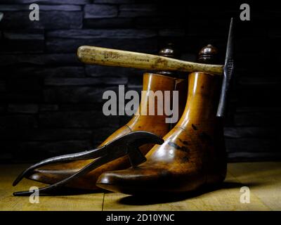 Ein Paar klassischer Schuster aus Holz und traditionelle Schuster Hammer 7 Zange dramatisch auf Holzbretter mit Schiefer beleuchtet Hintergrund Stockfoto