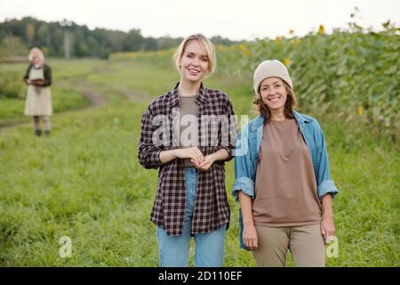 Zwei fröhliche Farmerinnen in Arbeitskleidung, die Sie mit betrachten Lächelt auf der Farm Stockfoto