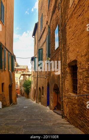 Blick auf eine schmale Gasse im historischen Zentrum von Siena, UNESCO-Weltkulturerbe, mit den typischen, alten Backsteinfassaden, Toskana, Italien Stockfoto