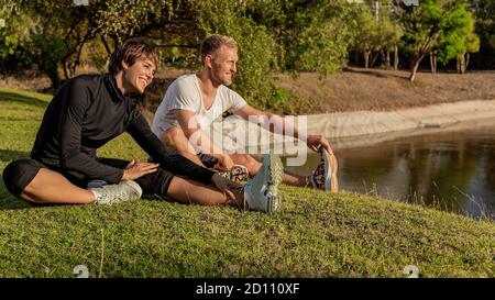 Ein Kerl mit einem Mädchen, das im Park ein Warm-up macht. Hochwertige Fotos Stockfoto