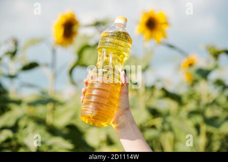 Hand der jungen zeitgenössischen Farmerin hält Flasche mit frisch Sonnenblumenöl Stockfoto