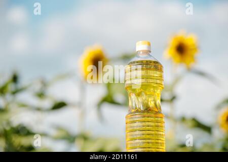 Plastikflasche mit frischem Sonnenblumenöl gegen Pflanzen mit großen Gelbe Blüten Stockfoto