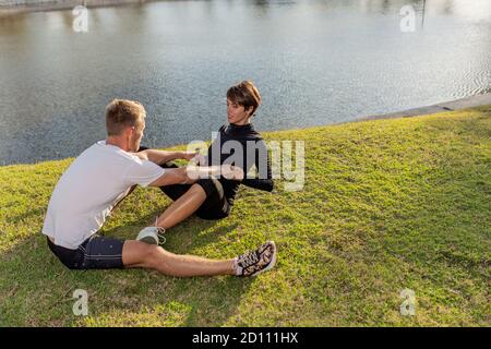 Ein Kerl mit einem Mädchen, das im Park ein Warm-up macht. Hochwertige Fotos Stockfoto