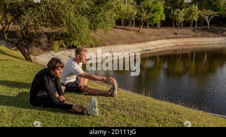 Ein Kerl mit einem Mädchen, das im Park ein Warm-up macht. Hochwertige Fotos Stockfoto