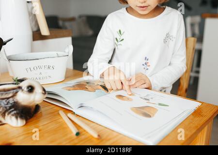 Kiew, Ukraine - 4. Oktober 2020: Kinder Wissenschaft Experiment - Kind Buch lesen Harvey der Gärtner auf ukrainisch lernen, Samen anzubauen. Kleines Mädchen mit Stockfoto