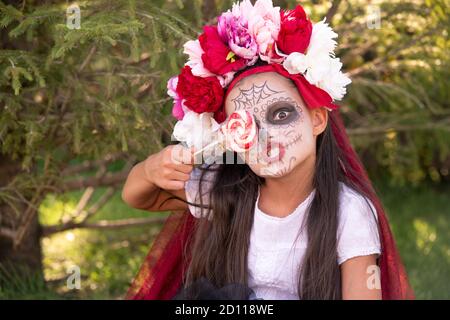 Brunette Mädchen mit Farbe auf Gesicht und große Lollypop von Augen erschrecken Sie Stockfoto