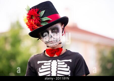 Gruseliger Junge mit bemaltem Gesicht im halloween Kostüm aus Skelett Mit eleganter Mütze Stockfoto