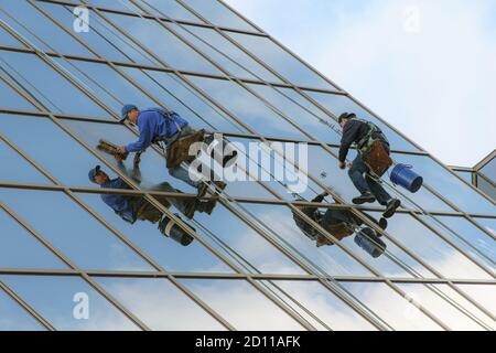 Zwei Wartungsarbeiter reinigen Fenster eines hohen Glasgebäudes Stockfoto