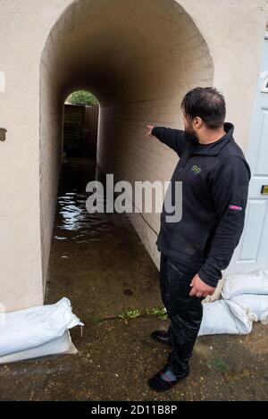 Aylesbury, Großbritannien. Oktober 2020. Sturm Alex Überschwemmungen in Aylesbury, Grafschaft Stadt Buckinghamshire. Ein Wochenende mit fast konstanten starken Regenfällen führte dazu, dass der Bear Brook seine Ufer überflutete Häuser in Southcourt Penn Road platzte. Als der fast ununterbrochene Regen nachlässt, beginnen die Bewohner den Schaden zu erreichen und beginnen aufzuräumen. Notdienste blockierten den Zugang zum überfluteten Bereich. Resident zeigt auf seine Eigenschaften überflutete Gasse. Quelle: Stephen Bell/Alamy Stockfoto