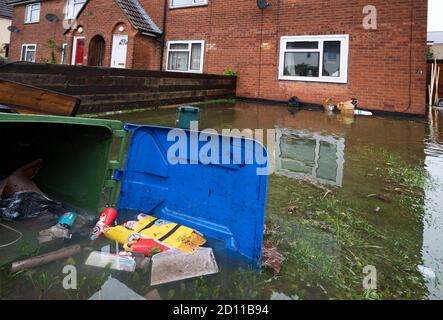 Aylesbury, Großbritannien. Oktober 2020. Sturm Alex Überschwemmungen in Aylesbury, Grafschaft Stadt Buckinghamshire. Ein Wochenende mit fast konstanten starken Regenfällen führte dazu, dass der Bear Brook seine Ufer überflutete Häuser in Southcourt Penn Road platzte. Als der fast ununterbrochene Regen nachlässt, beginnen die Bewohner den Schaden zu erreichen und beginnen aufzuräumen. Notdienste blockierten den Zugang zum überfluteten Bereich. Überflutetes Grundstück mit rubbeligen Mülltonnen auf der Seite und rubbelig schwimmend in überschwemmtem Vorgarten. Quelle: Stephen Bell/Alamy Stockfoto