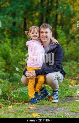 Ein Mädchen mit einem gebrochenen Arm umarmt ihren Vater Ein alter Park auf einem Herbstspaziergang Stockfoto