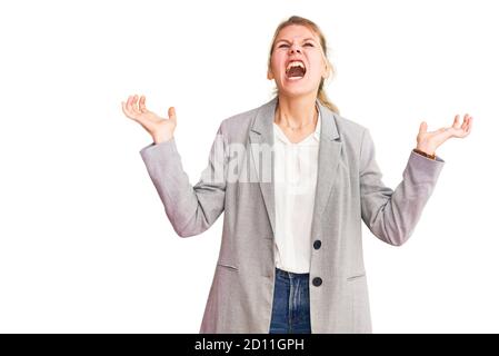 Junge schöne blonde Frau trägt elegante Jacke verrückt und verrückt schreien und mit aggressivem Ausdruck und Arme angehoben. Frustration Konzept Stockfoto