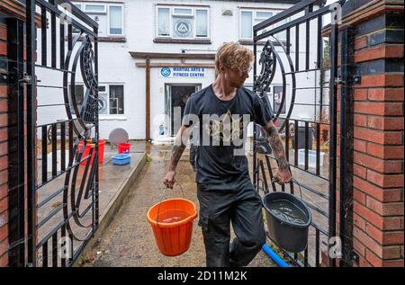 Aylesbury, Großbritannien. Oktober 2020. Sturm Alex Überschwemmungen in Aylesbury, Grafschaft Stadt Buckinghamshire. Ein Wochenende mit fast konstanten starken Regen veranlasste den Bear Brook, seine Ufer zu sprengen, bedrohte Häuser in Southcourt Kalifornien und überflutete das Martial Arts and Fitness Center. Als der fast ununterbrochene Regen nachließ, begann die Aufräumung des überfluteten Kampfsport- und Fitnesscenters mit Hilfe einer elektrischen Pumpe und Eimern. Quelle: Stephen Bell/Alamy Stockfoto