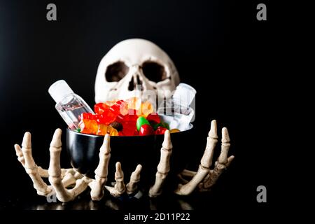 Skelett Kralle Hände mit Süßigkeiten und Hand Sanitizer - Halloween Konzept Stockfoto